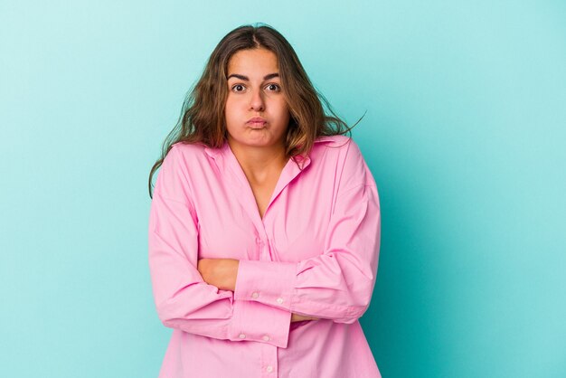 Jonge blanke vrouw geïsoleerd op blauwe achtergrond blaast wangen, heeft een vermoeide uitdrukking. Gezichtsuitdrukking concept.