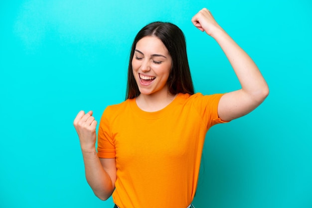 Jonge blanke vrouw geïsoleerd op blauwe achtergrond die een overwinning viert