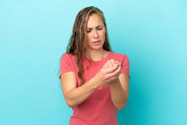 Jonge blanke vrouw geïsoleerd op blauwe achtergrond die lijdt aan pijn in handen