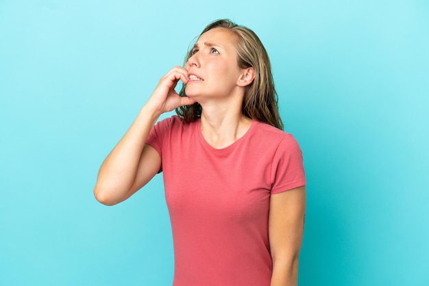 Jonge blanke vrouw geïsoleerd op blauwe achtergrond is een beetje nerveus