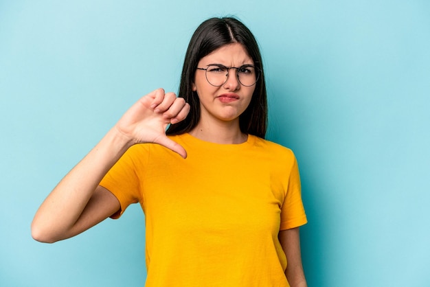 Jonge blanke vrouw geïsoleerd op blauwe achtergrond met duim omlaag teleurstelling concept