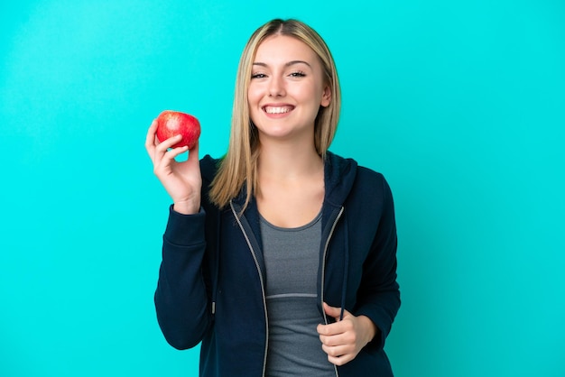 Jonge blanke vrouw geïsoleerd op blauwe achtergrond met een appel en happy