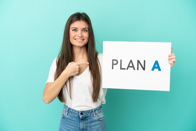 Jonge blanke vrouw geïsoleerd op blauwe achtergrond met een bordje met het bericht PLAN A en erop wijzend