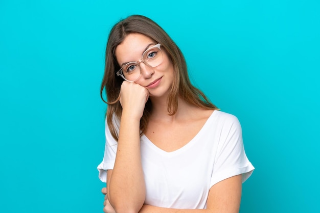 Jonge blanke vrouw geïsoleerd op blauwe achtergrond Met een bril en met droevige uitdrukking