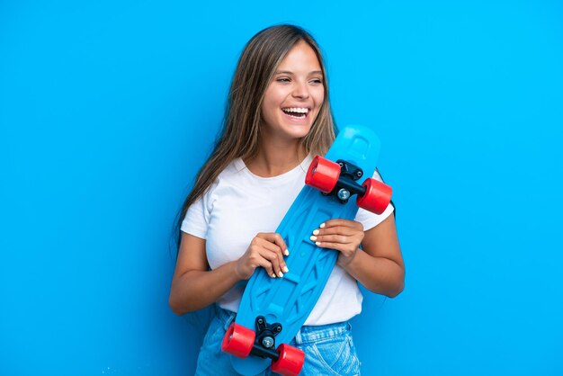 Jonge blanke vrouw geïsoleerd op blauwe achtergrond met een schaats met gelukkige expressie