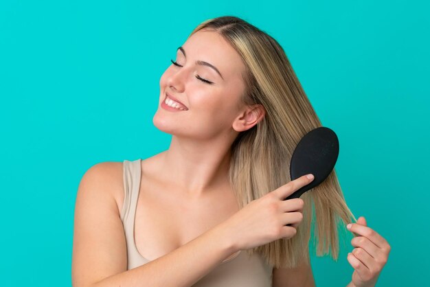 Jonge blanke vrouw geïsoleerd op blauwe achtergrond met haar comb