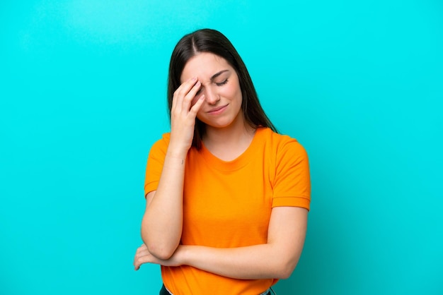 Jonge blanke vrouw geïsoleerd op blauwe achtergrond met hoofdpijn