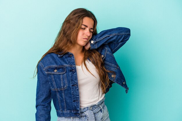 Jonge blanke vrouw geïsoleerd op blauwe achtergrond met nekpijn als gevolg van stress, masseren en aanraken met de hand.