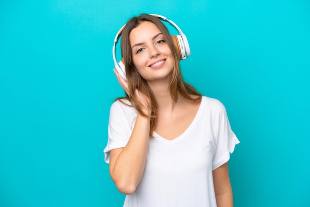 Jonge blanke vrouw geïsoleerd op blauwe achtergrond muziek luisteren