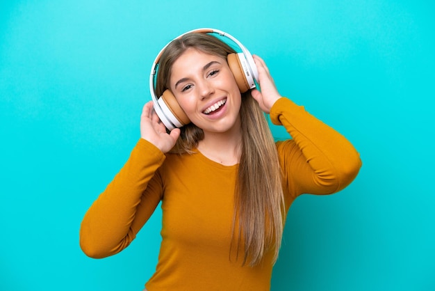 Jonge blanke vrouw geïsoleerd op blauwe achtergrond muziek luisteren