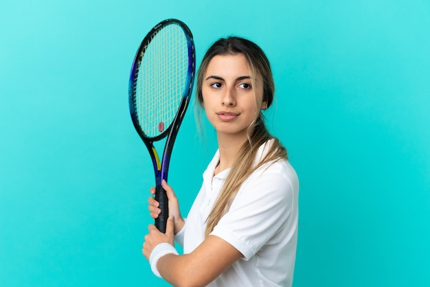 Jonge blanke vrouw geïsoleerd op blauwe achtergrond tennissen