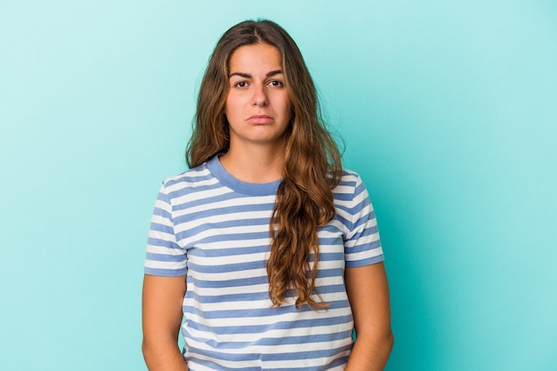 Jonge blanke vrouw geïsoleerd op blauwe achtergrond verdrietig, serieus gezicht, ellendig en ontevreden voelen.