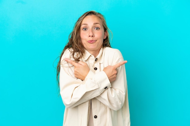 Jonge blanke vrouw geïsoleerd op blauwe achtergrond wijzend naar de zijtakken die twijfels hebben