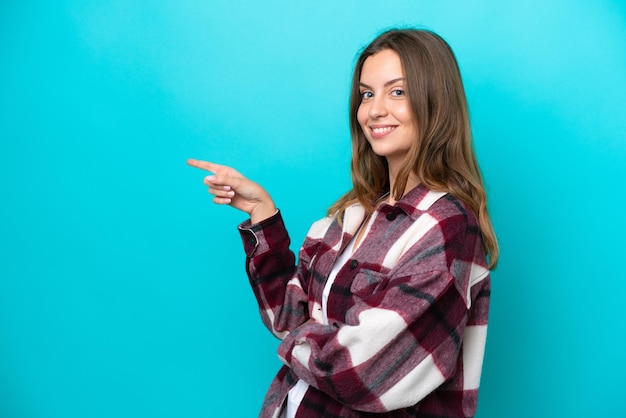 Jonge blanke vrouw geïsoleerd op blauwe achtergrond wijzende vinger naar de zijkant