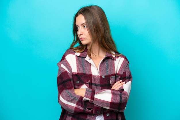 Jonge blanke vrouw geïsoleerd op een blauwe achtergrond die de armen gekruist houdt