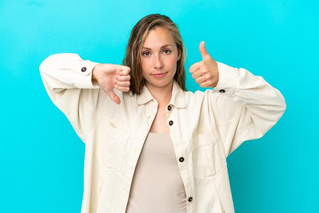 Jonge blanke vrouw geïsoleerd op een blauwe achtergrond die een goed teken maakt Onbeslist tussen ja of niet?