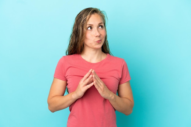 Jonge blanke vrouw geïsoleerd op een blauwe achtergrond die iets beraamt