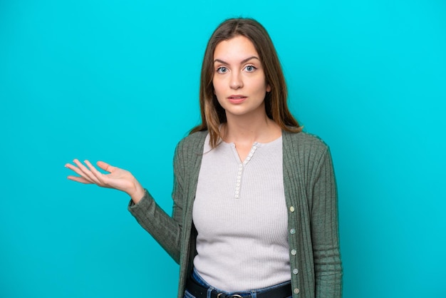 Jonge blanke vrouw geïsoleerd op een blauwe achtergrond die twijfels maakt