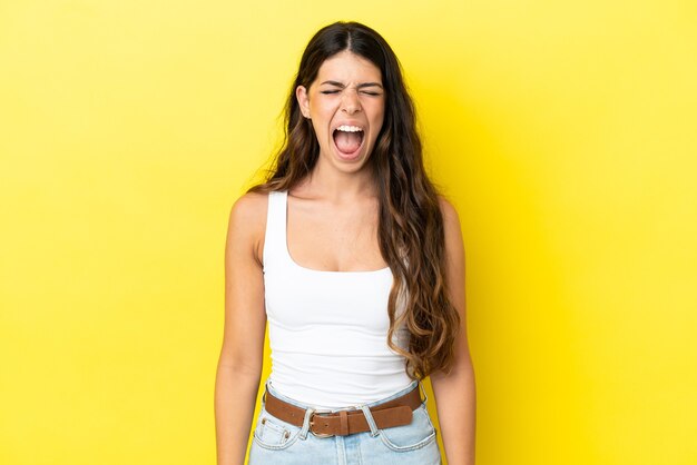 Jonge blanke vrouw geïsoleerd op een gele achtergrond die naar voren schreeuwt met wijd open mond