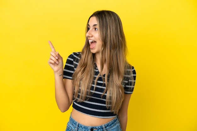 Jonge blanke vrouw geïsoleerd op een gele achtergrond die van plan is de oplossing te realiseren terwijl ze een vinger opheft