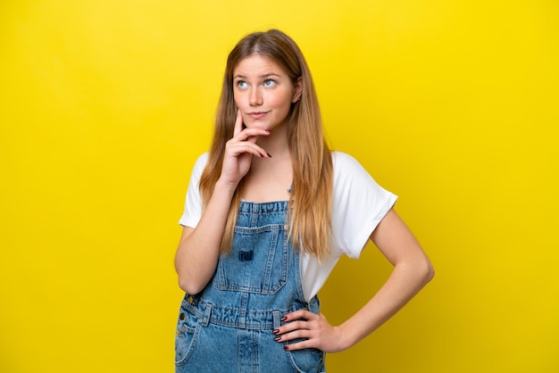 Jonge blanke vrouw geïsoleerd op een gele achtergrond met een idee terwijl ze naar boven kijkt