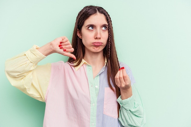 Jonge blanke vrouw geïsoleerd op een groene achtergrond waaruit blijkt dat ze geen geld heeft.