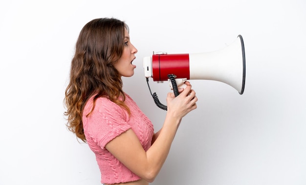 Jonge blanke vrouw geïsoleerd op een witte achtergrond die door een megafoon schreeuwt om iets in zijpositie aan te kondigen