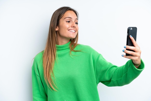 Jonge blanke vrouw geïsoleerd op een witte achtergrond die een selfie maakt