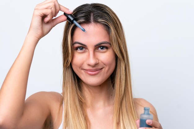 Jonge blanke vrouw geïsoleerd op een witte achtergrond die een serum vasthoudt terwijl ze lacht Close-up portret