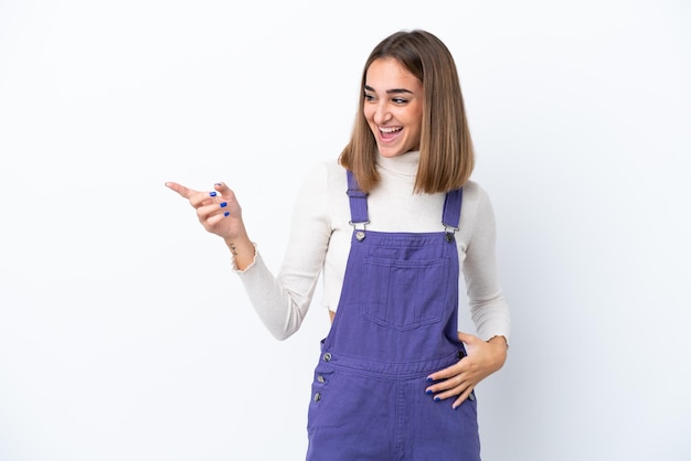 Jonge blanke vrouw geïsoleerd op een witte achtergrond die met de vinger naar de zijkant wijst en een product presenteert