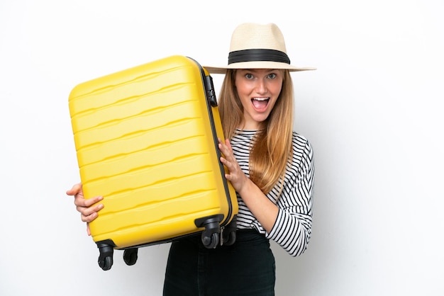 Jonge blanke vrouw geïsoleerd op een witte achtergrond in vakantie met reiskoffer en verrast