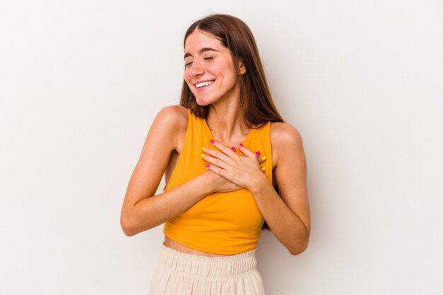 Jonge blanke vrouw geïsoleerd op een witte achtergrond lachen houden handen op het hart, concept van geluk.