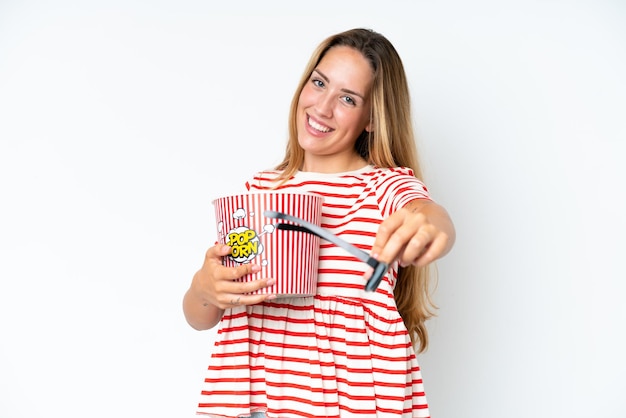 Jonge blanke vrouw geïsoleerd op een witte achtergrond met 3D-bril en met een grote emmer popcorn