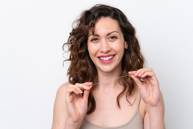 Jonge blanke vrouw geïsoleerd op een witte achtergrond met behulp van tandzijde met gelukkige uitdrukking Close-up portret