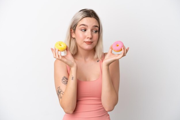 Jonge blanke vrouw geïsoleerd op een witte achtergrond met donuts