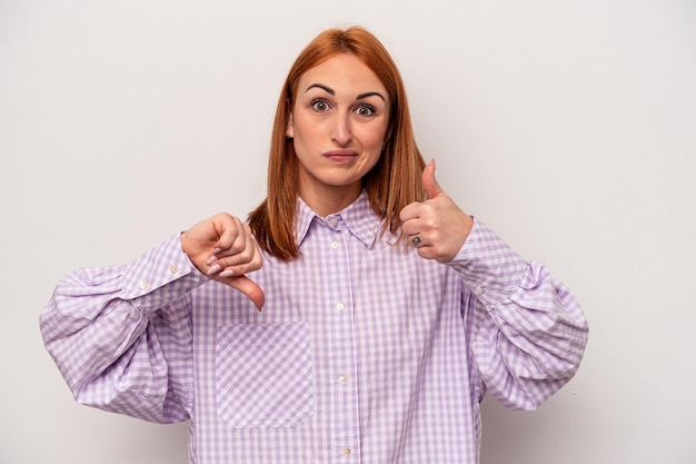 Foto jonge blanke vrouw geïsoleerd op een witte achtergrond met duimen omhoog en duim omlaag moeilijk kiezen concept