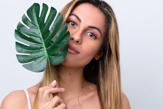 Jonge blanke vrouw geïsoleerd op een witte achtergrond met een palmblad Close-up portret