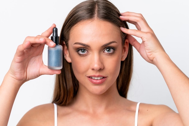 Jonge blanke vrouw geïsoleerd op een witte achtergrond met een serum close-up portret