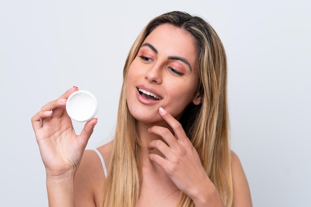 Jonge blanke vrouw geïsoleerd op een witte achtergrond met moisturizer