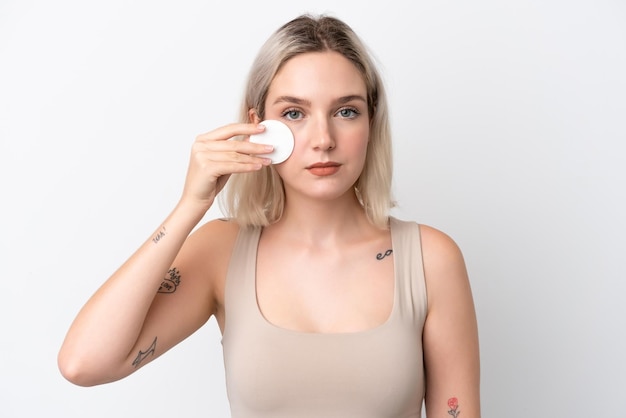 Jonge blanke vrouw geïsoleerd op een witte achtergrond met wattenschijfje voor het verwijderen van make-up van haar gezicht