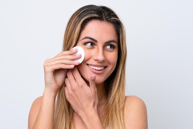 Jonge blanke vrouw geïsoleerd op een witte achtergrond met wattenschijfje voor het verwijderen van make-up van haar gezicht