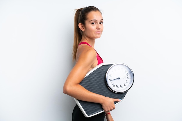 Jonge blanke vrouw geïsoleerd op een witte achtergrond met weegmachine