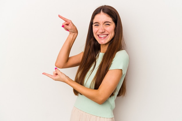 Jonge blanke vrouw geïsoleerd op een witte achtergrond opgewonden wijzend met wijsvingers weg.