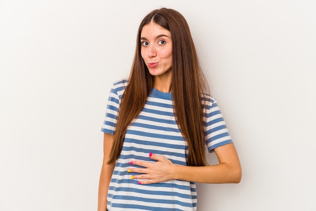 Jonge blanke vrouw geïsoleerd op een witte achtergrond raakt buik, glimlacht zachtjes, eten en tevredenheid concept.