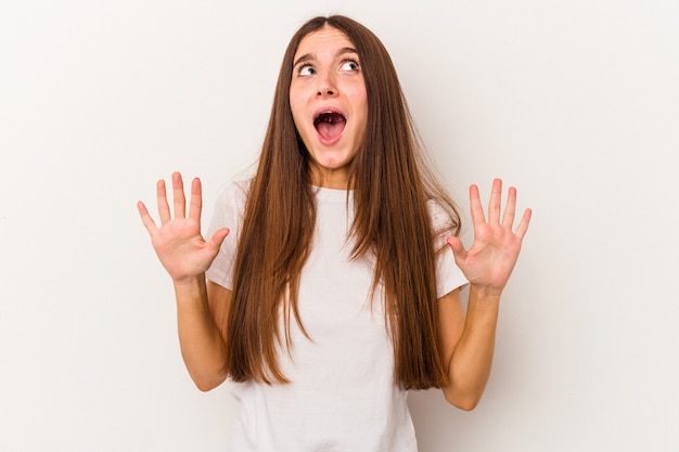 Jonge blanke vrouw geïsoleerd op een witte achtergrond schreeuwen naar de hemel, opzoeken, gefrustreerd.