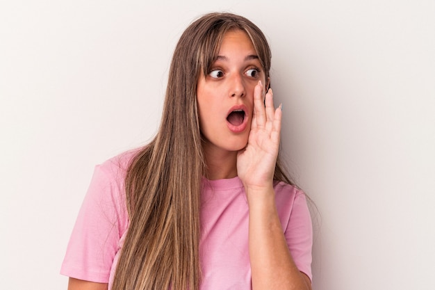 Jonge blanke vrouw geïsoleerd op een witte achtergrond wordt geschokt vanwege iets dat ze heeft gezien.