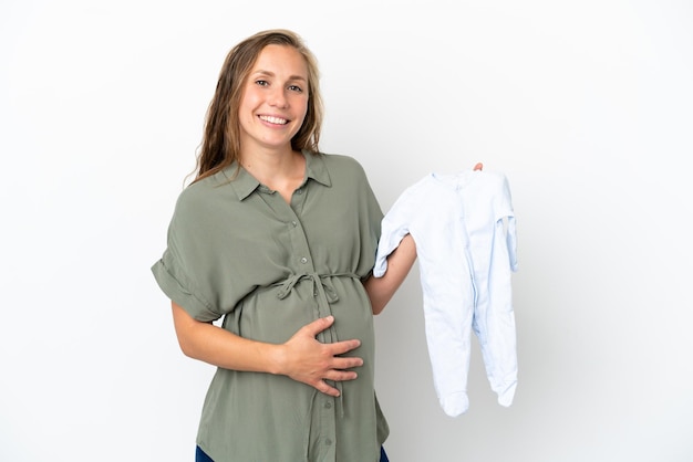 Jonge blanke vrouw geïsoleerd op een witte achtergrond zwanger en met babykleertjes