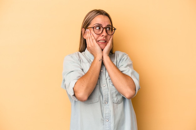 Jonge blanke vrouw geïsoleerd op gele achtergrond bang en bang.