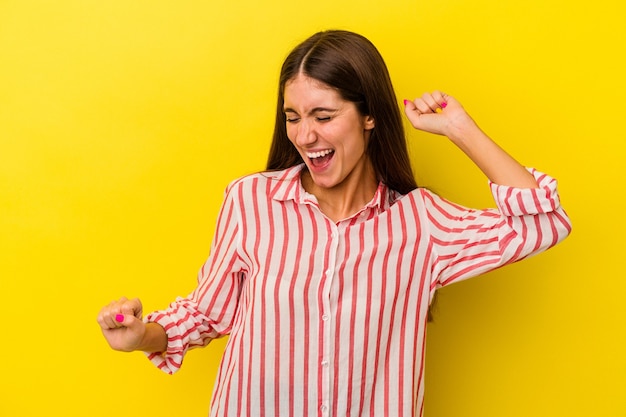 Jonge blanke vrouw geïsoleerd op gele achtergrond dansen en plezier maken.