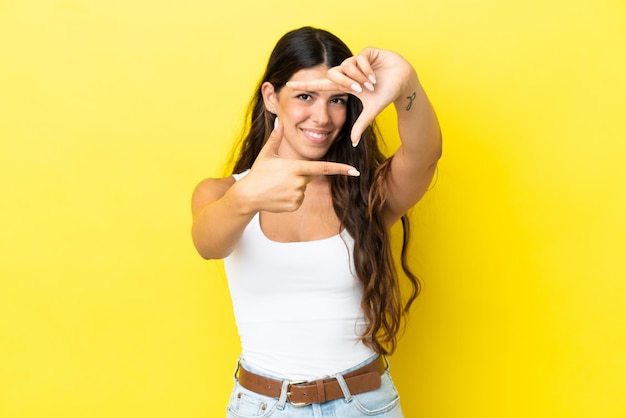 Jonge blanke vrouw geïsoleerd op gele achtergrond gericht gezicht. Frame symbool